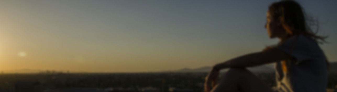 An ASU student on top of A mountain, viewing a sunset.